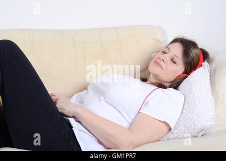 Porträt einer schönen Frau, Musik hören und entspannen auf dem Sofa. Indoor. Stockfoto