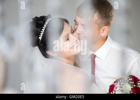 Junge fröhliche kaukasischen Hochzeitspaar Lachen und Kuscheln im Freien. Schöne glückliche Braut umarmen und küssen mit gut aussehend Stockfoto