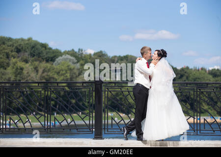 Junge kaukasischen Hochzeitspaar umarmt auf der Brücke. Seite Ansicht Porträt des Brautpaares sahen einander mit Liebe Stockfoto