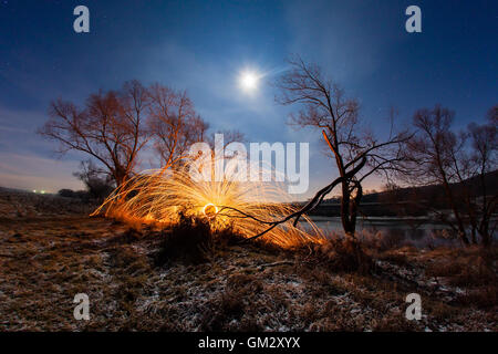 Nacht-Winterlandschaft und Funken aus dem brennenden Stahlwolle Stockfoto