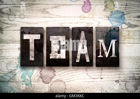 Das Wort "TEAM" auf einem weiß getünchten hölzernen Hintergrund mit Tinte und Farbe Flecken in Vintage schmutzig Metall Buchdruck Art geschrieben. Stockfoto
