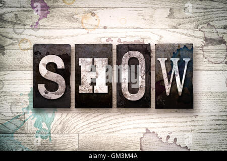 Das Wort "SHOW" auf einem weiß getünchten hölzernen Hintergrund mit Tinte und Farbe Flecken in Vintage schmutzig Metall Buchdruck Art geschrieben. Stockfoto