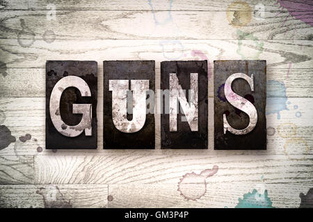 Das Wort "GUNS" geschrieben in Vintage schmutzig Metall Buchdruck Typ auf einem weiß getünchten hölzernen Hintergrund mit Tinte und Farbe Flecken. Stockfoto