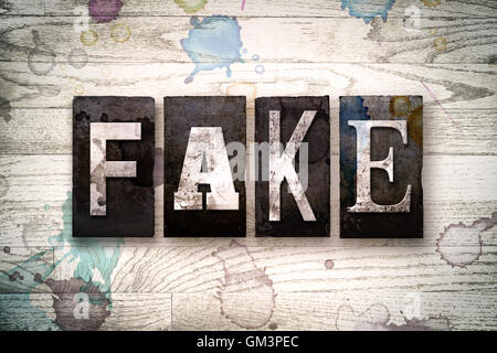 Das Wort 'FAKE' geschrieben in Vintage schmutzig Metall Buchdruck Typ auf einem weiß getünchten hölzernen Hintergrund mit Tinte und Farbe Flecken. Stockfoto