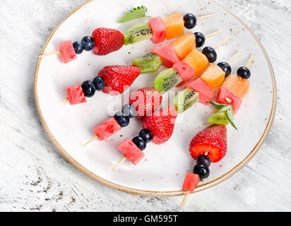 Colorful fresh fruit kebabs on a plate. Healthy eating Stockfoto