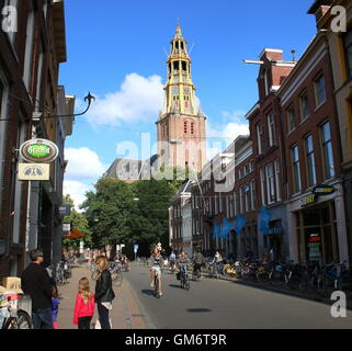 Menschen beim Einkaufen in Brugstraat (Bridge Street) in Groningen, Niederlande. 17. Jahrhundert Kirche Der Aa-Kerk im Hintergrund. Stockfoto