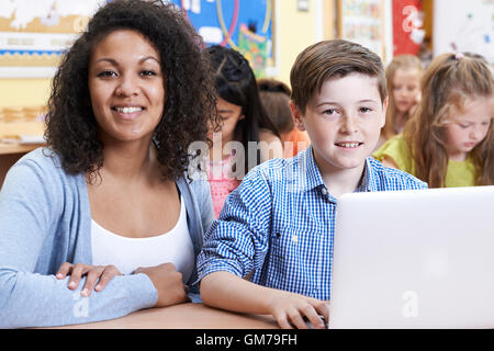 Lehrer helfen männlichen Grundschule Schüler im Informatikunterricht Stockfoto