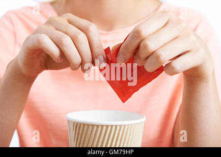 Frau Kaffee mit Süßstoff hinzufügen Stockfoto