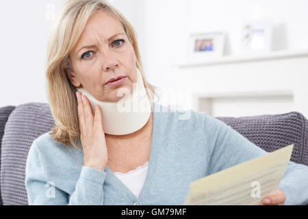 Reife Frau lesen schreiben nach Erhalt Nackenverletzung Stockfoto