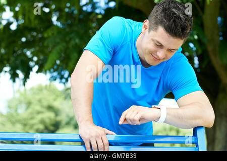 Man Looking At Aktivitätsprotokoll während des Trainings im Park Stockfoto