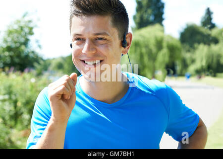 Der junge Mann läuft im Park Musik hautnah Stockfoto
