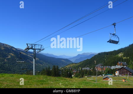 Meribel Skigebiet in den französischen Alpen im Sommer; Weide, Seilbahn, Sessellift, Chalets, blauer Himmel Stockfoto