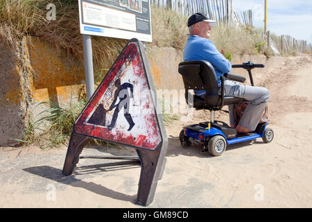 Behinderte Mensch auf Mobilität Motorroller, Mariners Weg, Crosby, Liverpool, Merseyside, Großbritannien Stockfoto