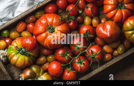 Bunte Tomaten in verschiedenen Größen und Arten in dunklen Holztablett Stockfoto