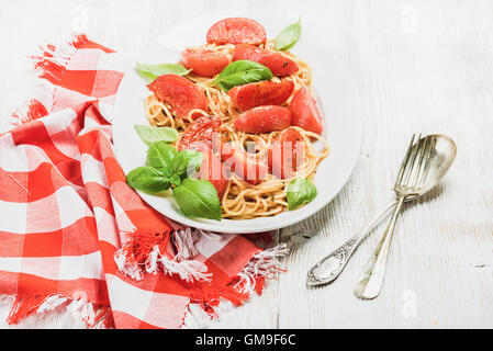 Spaghetti mit gebratenen Tomaten und frischem Basilikum auf weißem Hintergrund Stockfoto