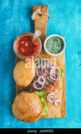 Hausgemachte Rindfleisch-Burger mit Zwiebeln, frischem Gemüse, Gewürze, Tomatensoße Stockfoto