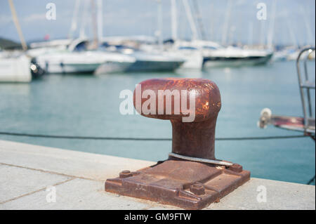 Verrostete Festmacher Poller im dock der Hafen Pier, Segelboot im Hintergrund unscharf Stockfoto