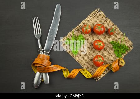 Tomaten wie Diätkost. Zubereitung von gesunden Mahlzeiten. Frisches Gemüse auf einem Holztisch. Stockfoto