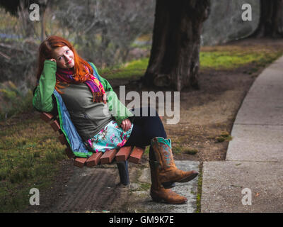Junge Frau sitzt auf der Bank im park Stockfoto