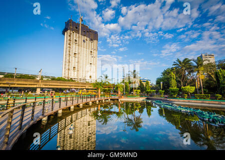 Teich im Rizal Park und Hochhaus im Bau, in Ermita/Intramuros, Manila, Philippinen. Stockfoto