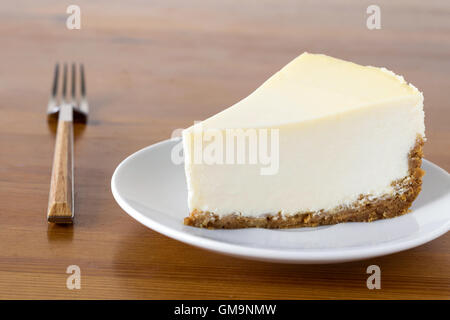 Stück schlicht New York Cheesecake auf weißen Teller auf Holztisch, Nahaufnahme Blick Stockfoto