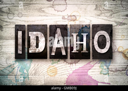 Das Wort "IDAHO" geschrieben in Vintage schmutzig Metall Buchdruck Typ auf einem weiß getünchten hölzernen Hintergrund mit Tinte und Farbe Flecken. Stockfoto