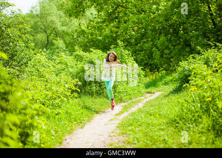Glückliche kleine Mädchen laufen im Sommerpark Stockfoto