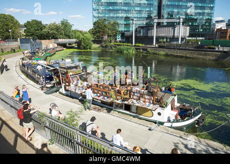 Regents Canal, King's Cross, London, UK: Word auf dem Wasser schwimmenden Buchhandlung, Menschen entspannen auf dem Treidelpfad Jazz hören. Stockfoto