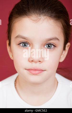 Studioportrait für ein hübsches kleines Mädchen auf einem Burgunder Hintergrund Stockfoto