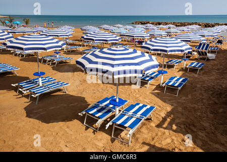 Sonnenschirme und Liegestühle am Strand, Marina Di Ragusa, Sizilien, Italien Stockfoto