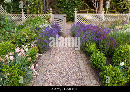 Geöffnete Tor, Pfad und Lavendel Blüten in schönen, traditionellen, gestaltete, gepflegten, privaten Garten - North Yorkshire, England. Stockfoto