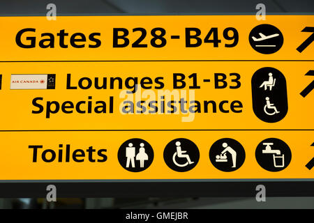 Wegweiser zu den speziellen Hilfe-Lounges am Flughafen Heathrow Terminal 2 & Toilette / WC / Waschbecken Toilette. London Stockfoto