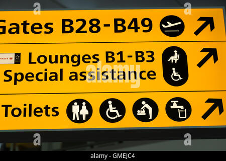 Wegweiser zu den speziellen Hilfe-Lounges am Flughafen Heathrow Terminal 2 & Toilette / WC / Waschbecken Toilette. London Stockfoto
