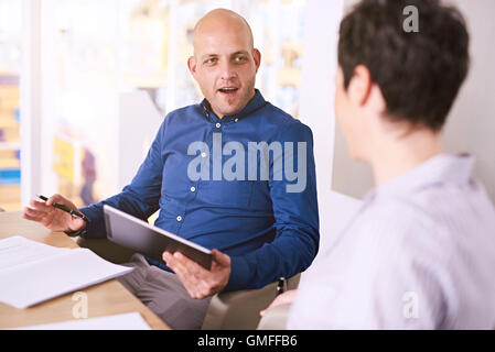 junger Mann Betrieb Tablet während eines Treffens mit Business-Frau Stockfoto