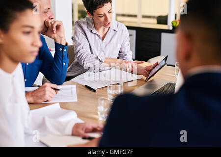 Reife Geschäftsfrau zeigt ihren männlichen Kollegen Analyseinformationen auf Tablet Stockfoto