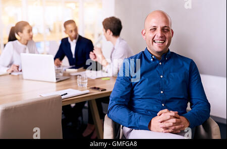 Glücklich und stolz Geschäftsmann vertritt sein Team hinter ihm sitzen Stockfoto