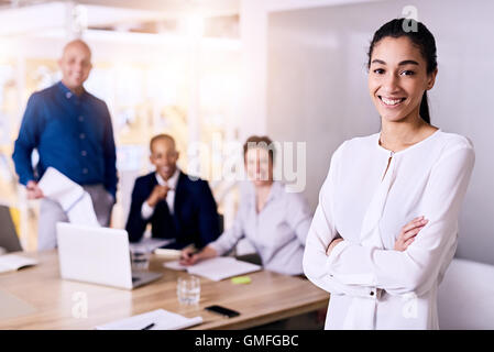 Business-Frau und ihr Team, die alle einen Blick auf die Kamera zu Lächeln Stockfoto