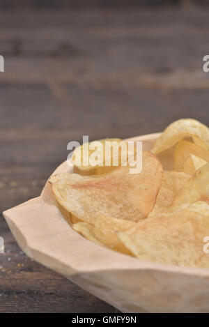 Gold gesalzene Kartoffelchips in einer Holzschale auf einem rustikalen braunen Tisch Stockfoto