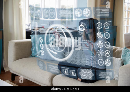 Frau sitzt auf dem Sofa zu Hause tragen Virtual-Reality-Kopfhörer Stockfoto