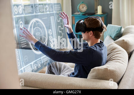 Mann sitzt auf dem Sofa zu Hause tragen Virtual-Reality-Kopfhörer Stockfoto