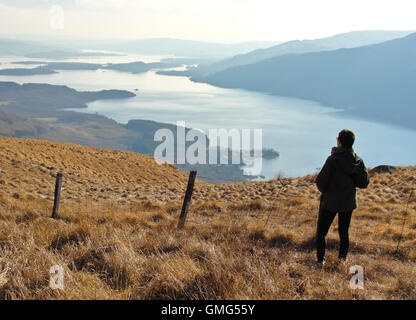 Eine Person, die auf der Oberseite des Ben Lomond (Schottland) mit Blick auf einen herrlichen Blick auf Loch Lomond Stockfoto