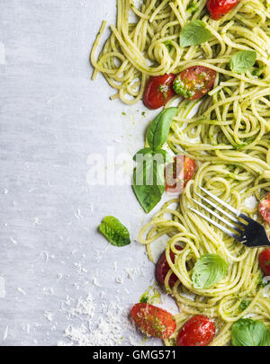 Spaghetti mit Pesto-Sauce, gebratenen Kirschtomaten, frischem Basilikum und Parmesan-Käse auf Stahl Hintergrund Stockfoto