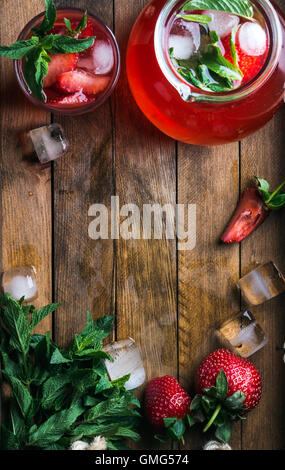 Hausgemachte Erdbeer Minze Limonade serviert mit frischen Beeren und Eis über hölzerne Hintergrund, Draufsicht, Textfreiraum Stockfoto