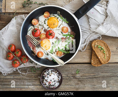 Pfanne mit Spiegelei, Speck und Cherry-Tomaten mit Brot Stockfoto