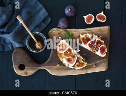 Sandwiches mit Ricotta, frische Feigen, Walnüssen und Honig auf rustikalem Holzbrett Stockfoto