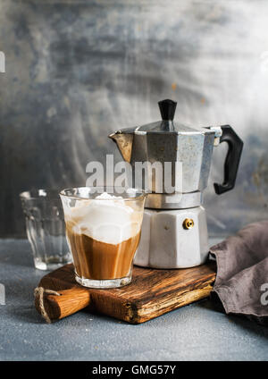 Glas Kaffee mit Eis auf rustikalem Holzbrett und italienischen Moka Stahltopf Stockfoto