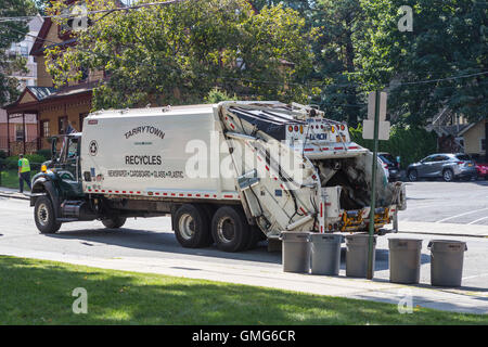 Sanitation Arbeiter sammeln Wertstoffe mit einem Müllwagen hinten-laden auf einer Straße in Tarrytown, New York.