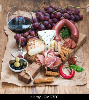 Glas Rot Wein, Käse und Fleisch Board, Trauben, Feigen, Erdbeeren, Honig, Brot klebt am rustikalen Holztisch, weißer Hintergrund Stockfoto