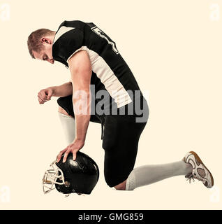 US-amerikanischer Footballspieler, kniete auf einem Knie, Kopf gebeugt. Getönten Foto. Stockfoto