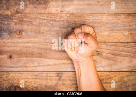 A man Fäuste geballt auf einem Holztisch im Zorn Stockfoto